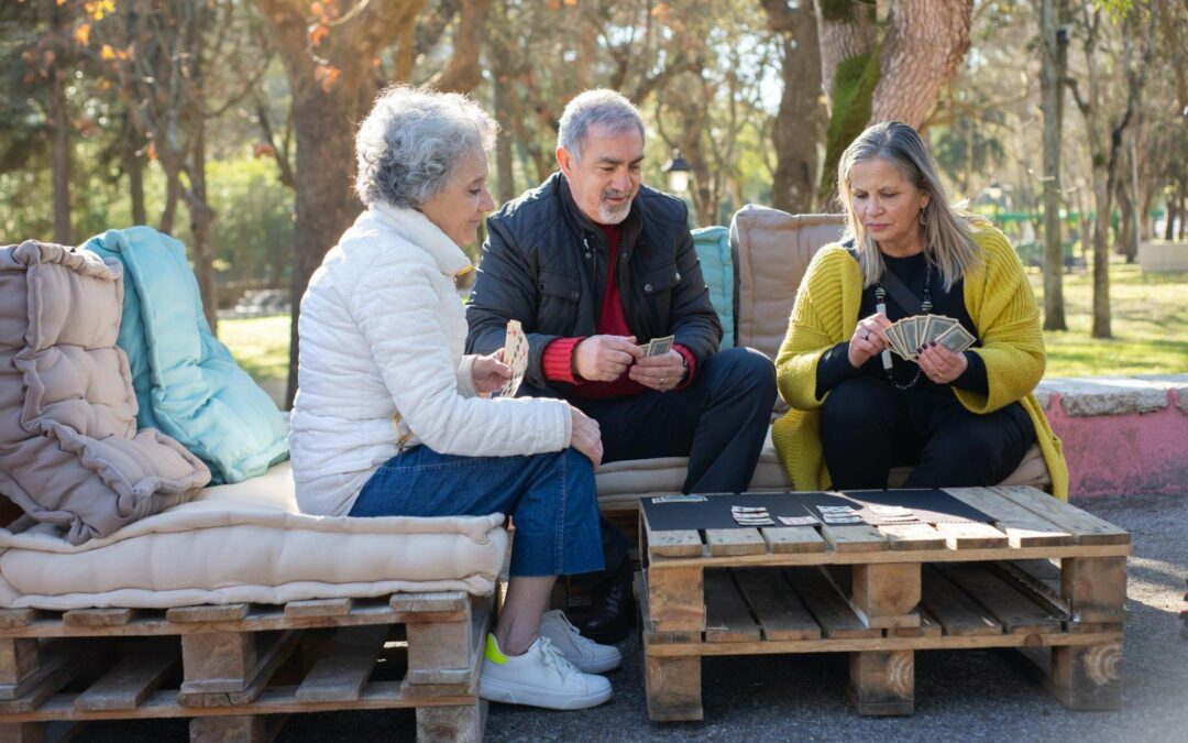 three elderly people sitting on a pallet playing a game